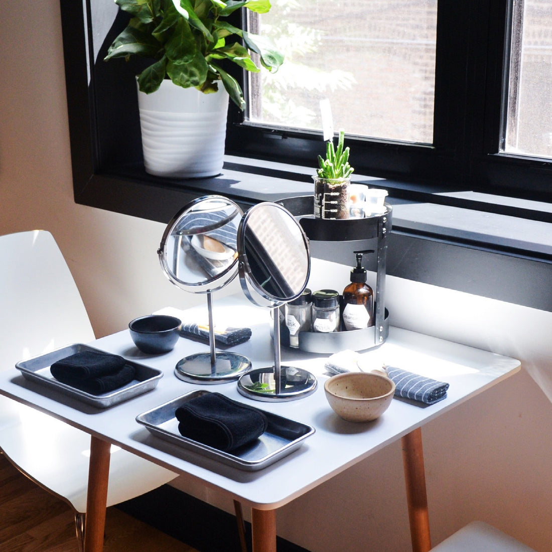  a table set for two with bowls, trays, napkins, spoons, mirrors, and a skincare carousel